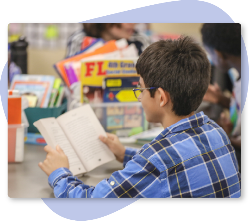 Student Reading Photo A young boy reading a short novel at a table.