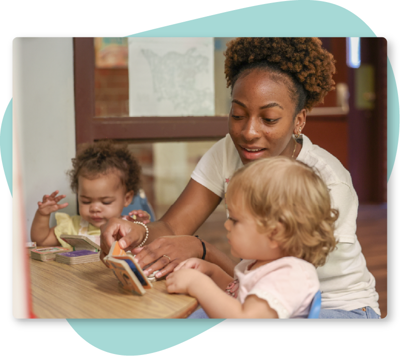 Teacher Helping a Student Read Photo A young woman teacher helping two toddlers with alphabet books.