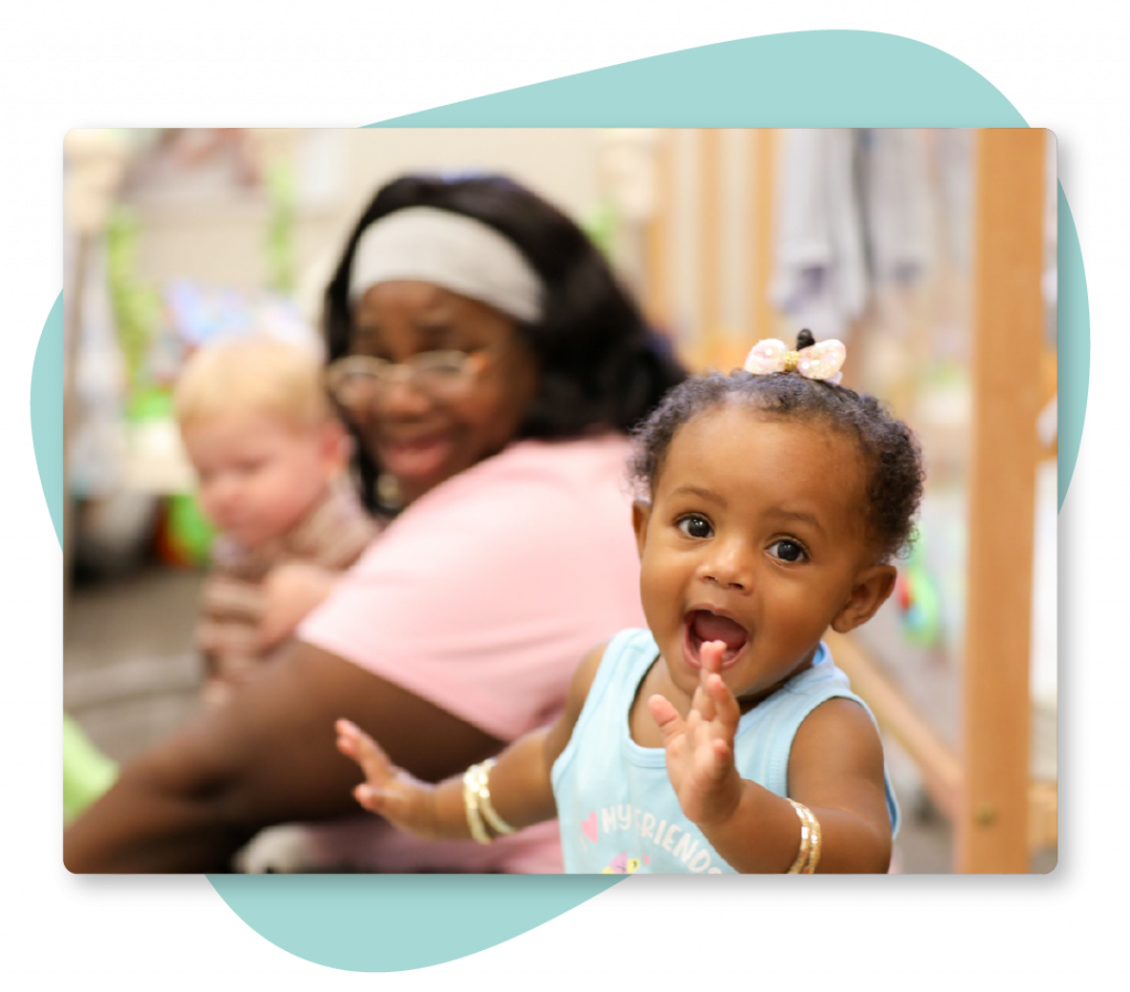 A young girl laughing while her early learning teacher laughs with her.